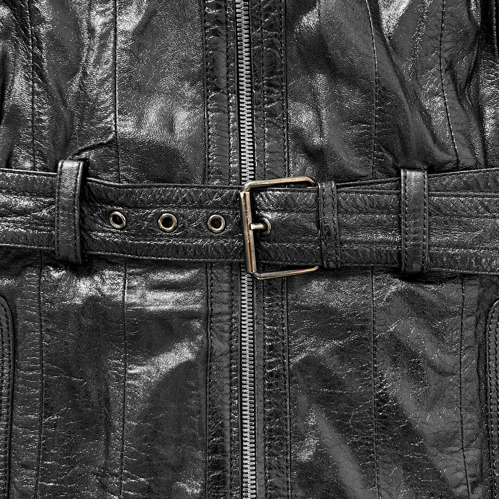 A close-up view of a black leather jacket with a metal buckle and a zipper.