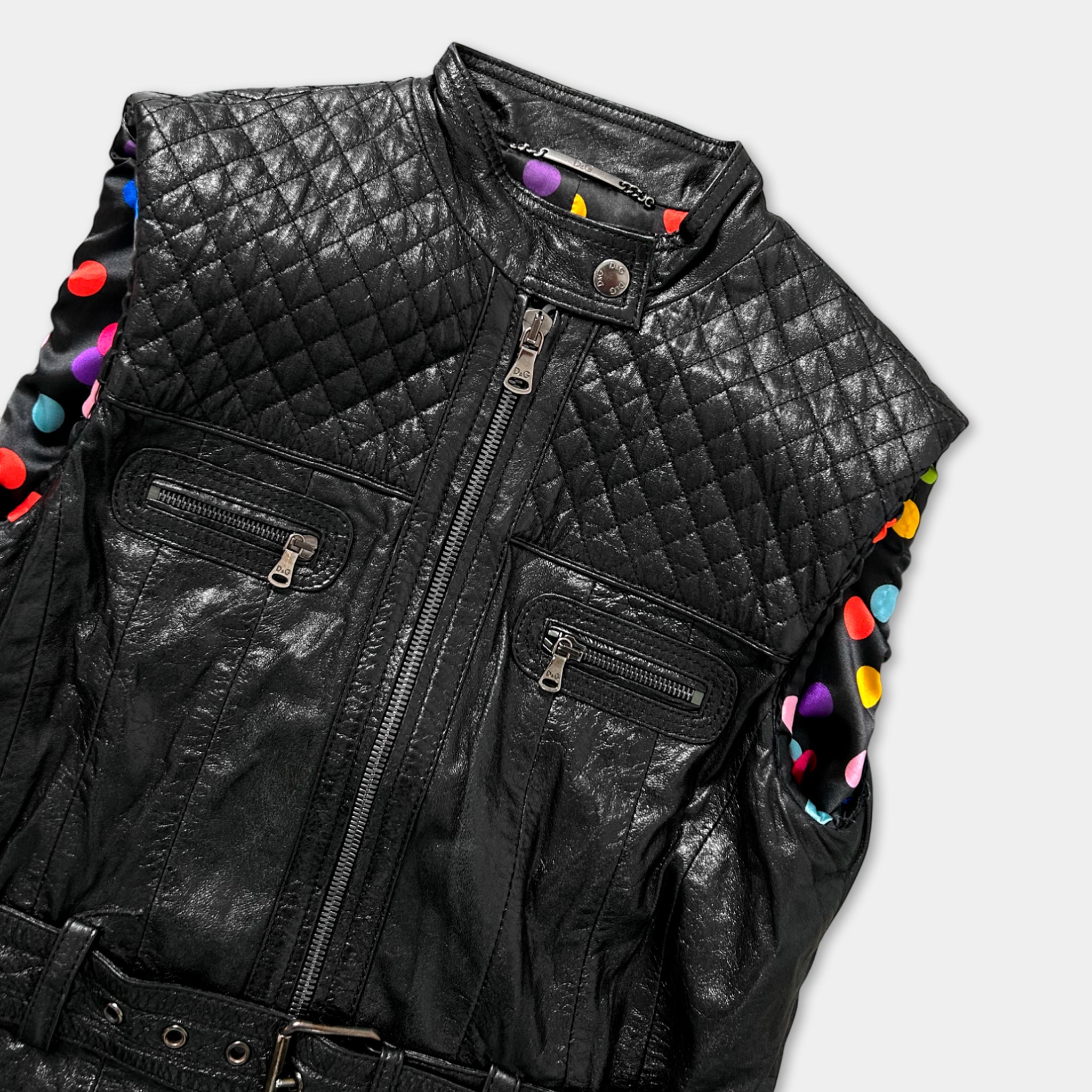 A black leather vest with colorful polka dots on the sleeves and collar.