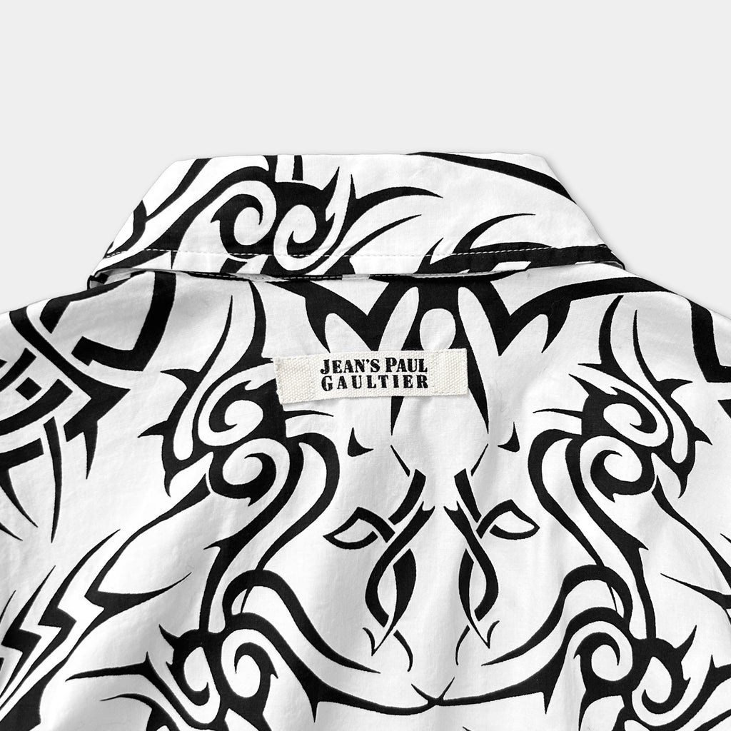 the back of a white shirt with a black and white tribal pattern. There is a label on the shirt that reads "Jean's Paul Gaultier".