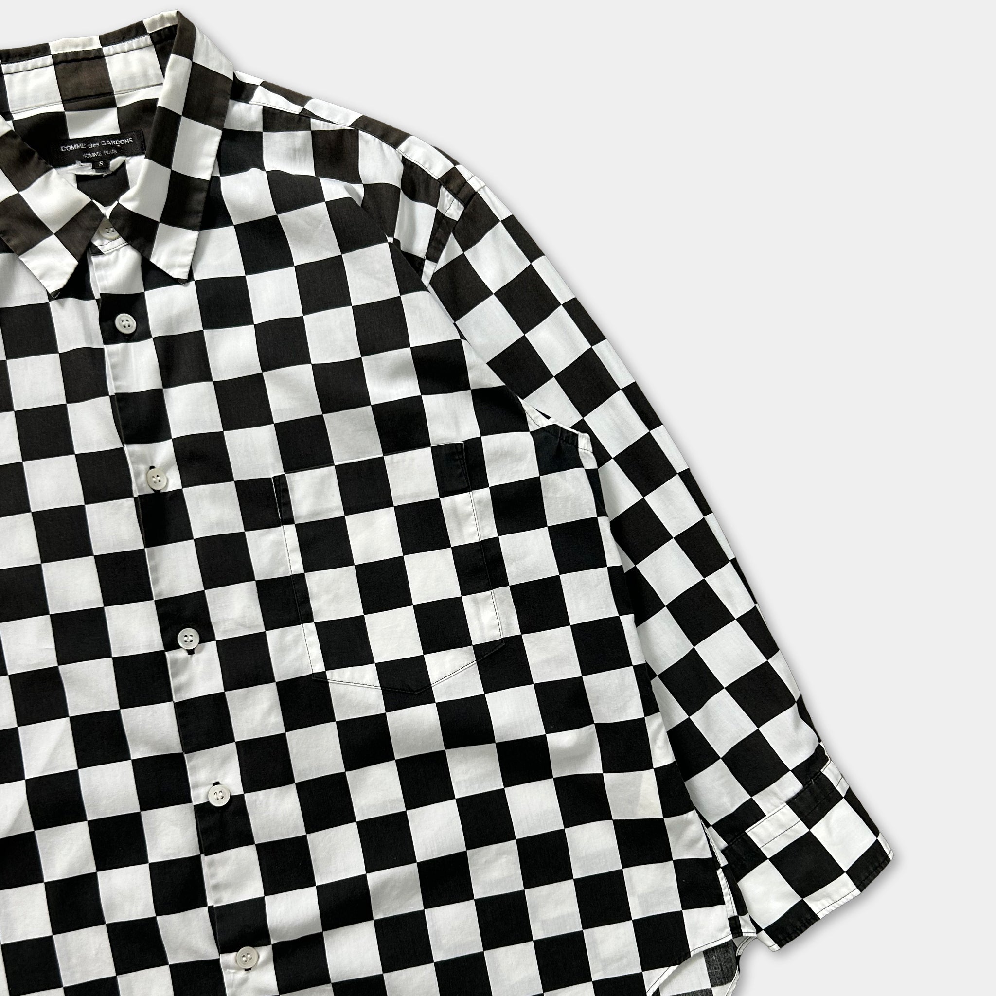 A black and white checkered shirt is displayed on a white background.
