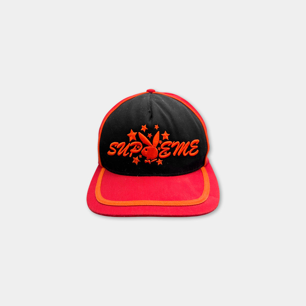 A red and black baseball cap with the word "SUPREME" printed on it.