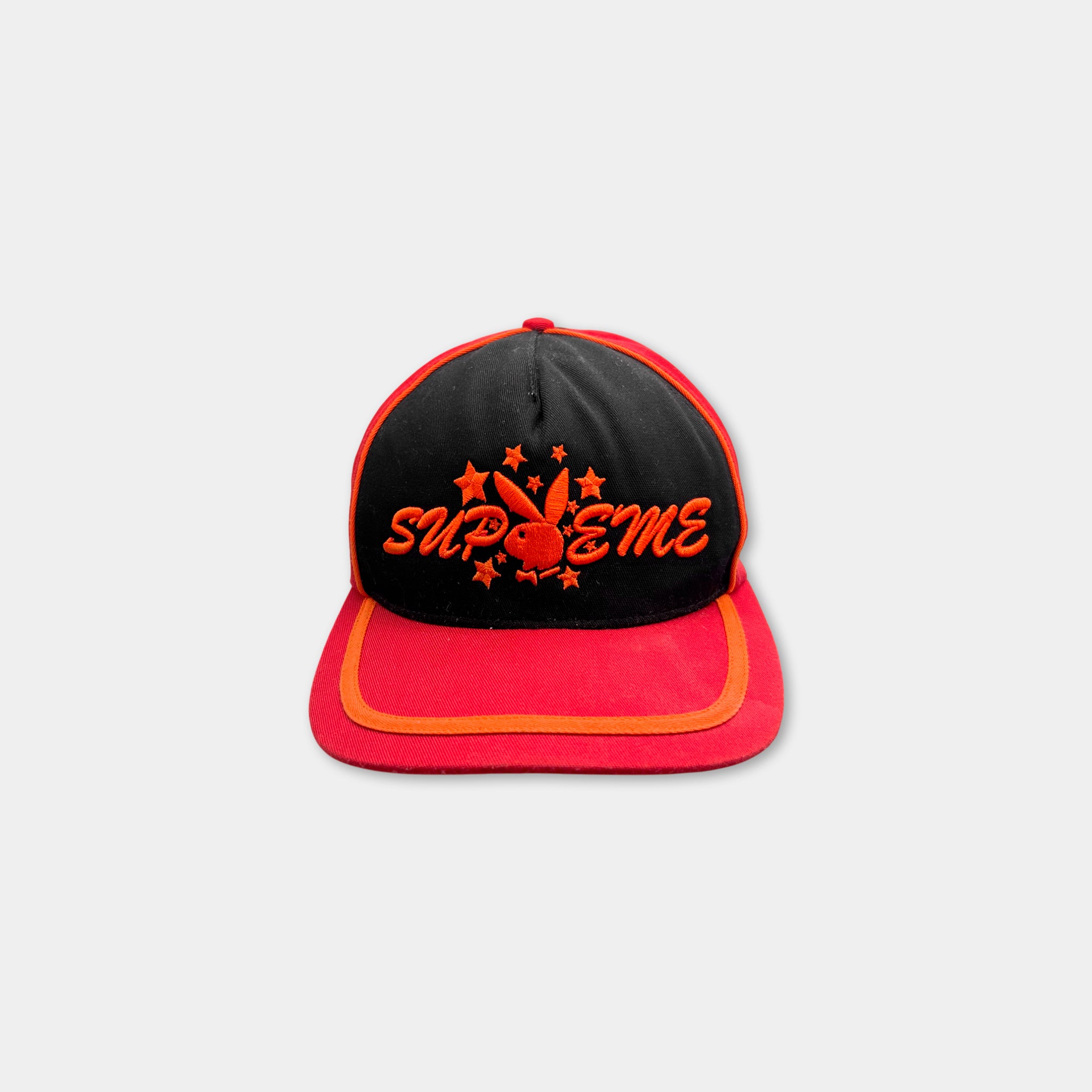 A red and black baseball cap with the word "SUPREME" printed on it.