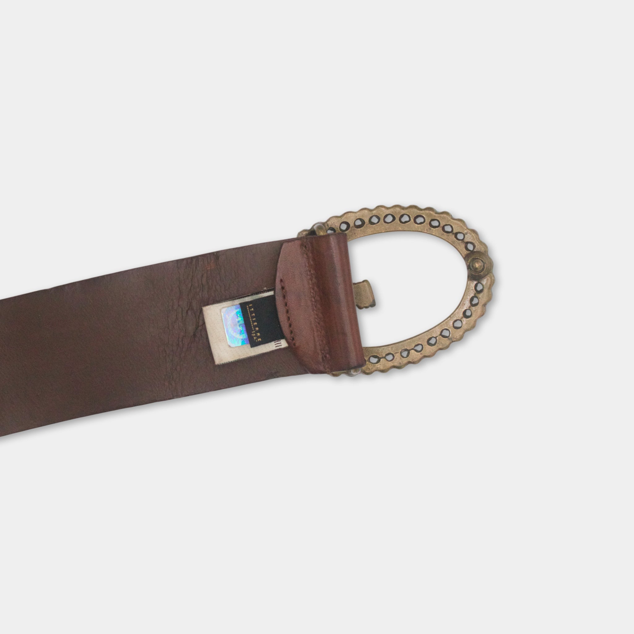 A brown leather belt with a metal buckle and a small card or label attached to it.