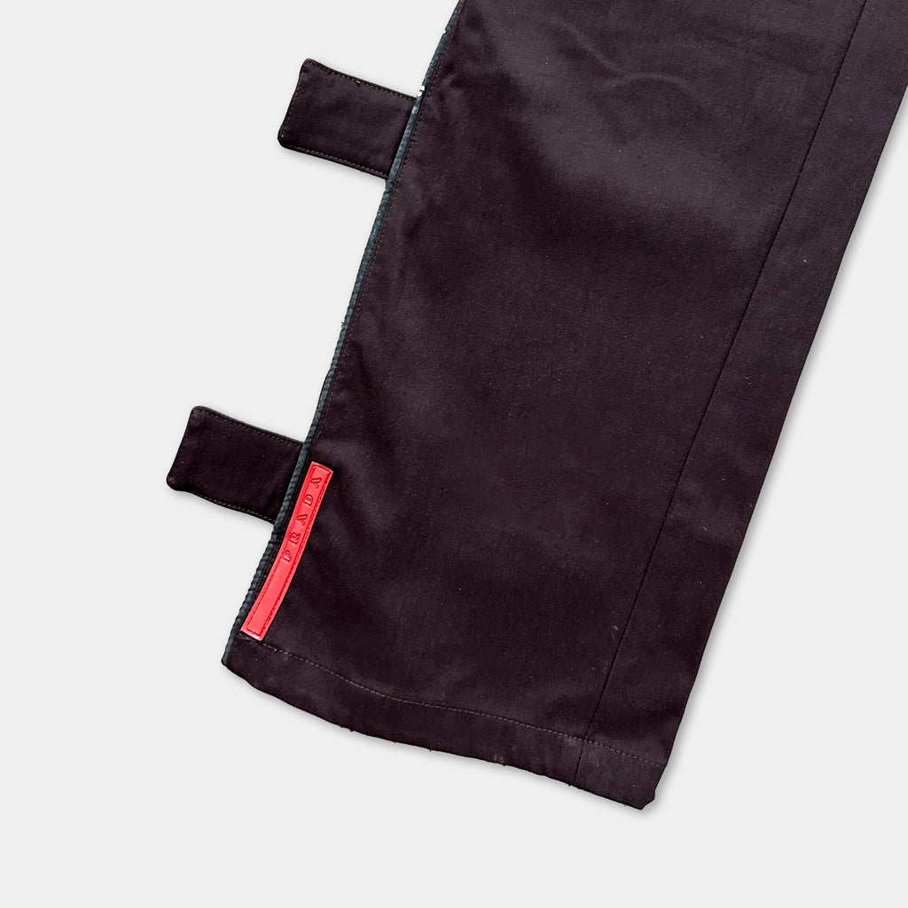 a close-up view of a dark-colored fabric, possibly a pair of pants or a jacket, with a red label or tag attached to it.