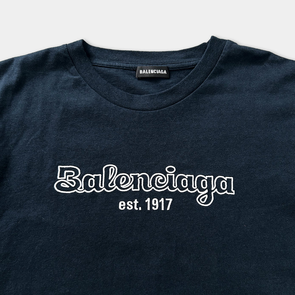 A navy blue t-shirt with the text "Balenciaga est. 1917" printed on it.