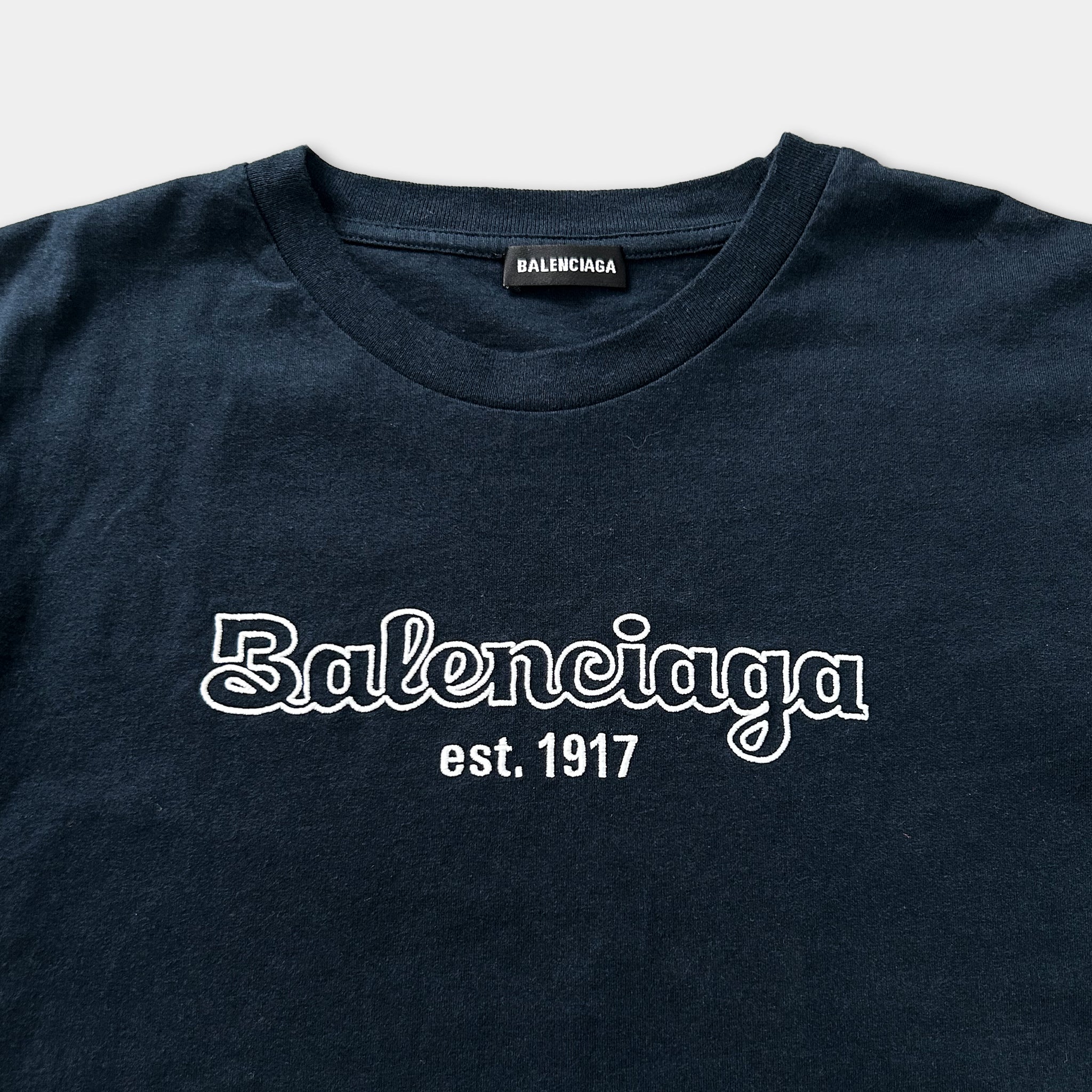 A navy blue t-shirt with the text "Balenciaga est. 1917" printed on it.