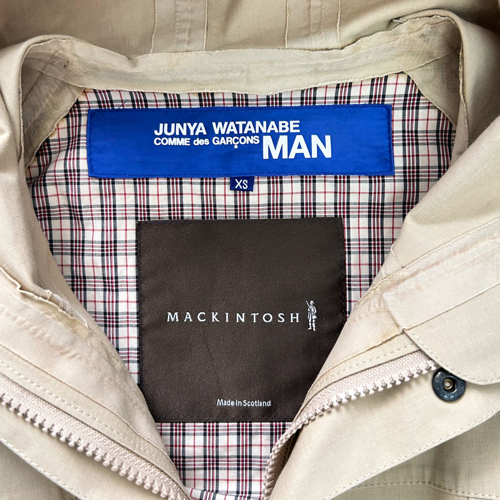 a close-up view of a beige jacket with a blue label and a brown tag, indicating the brand and size of the jacket.