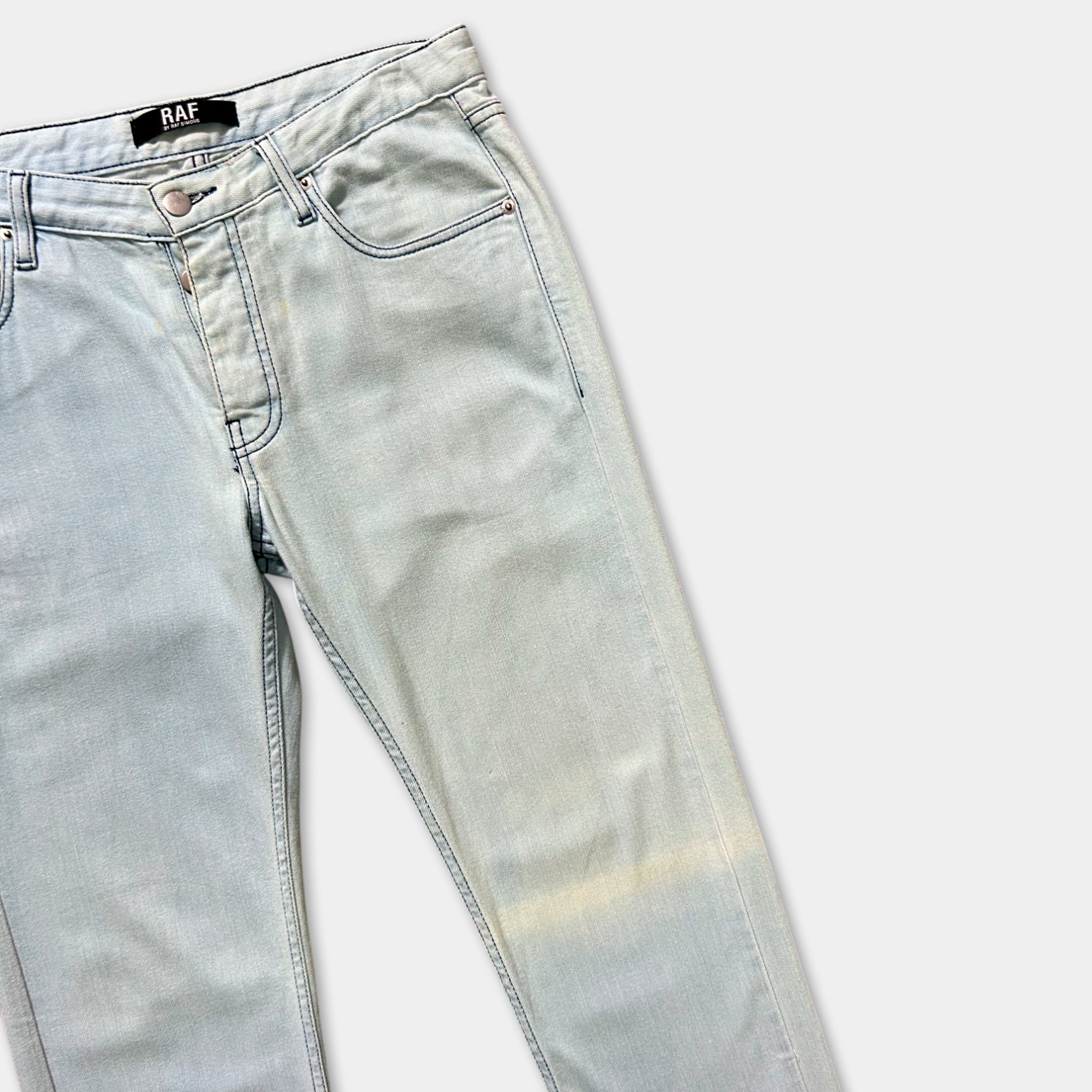 A pair of light blue denim jeans with a label on the waistband.