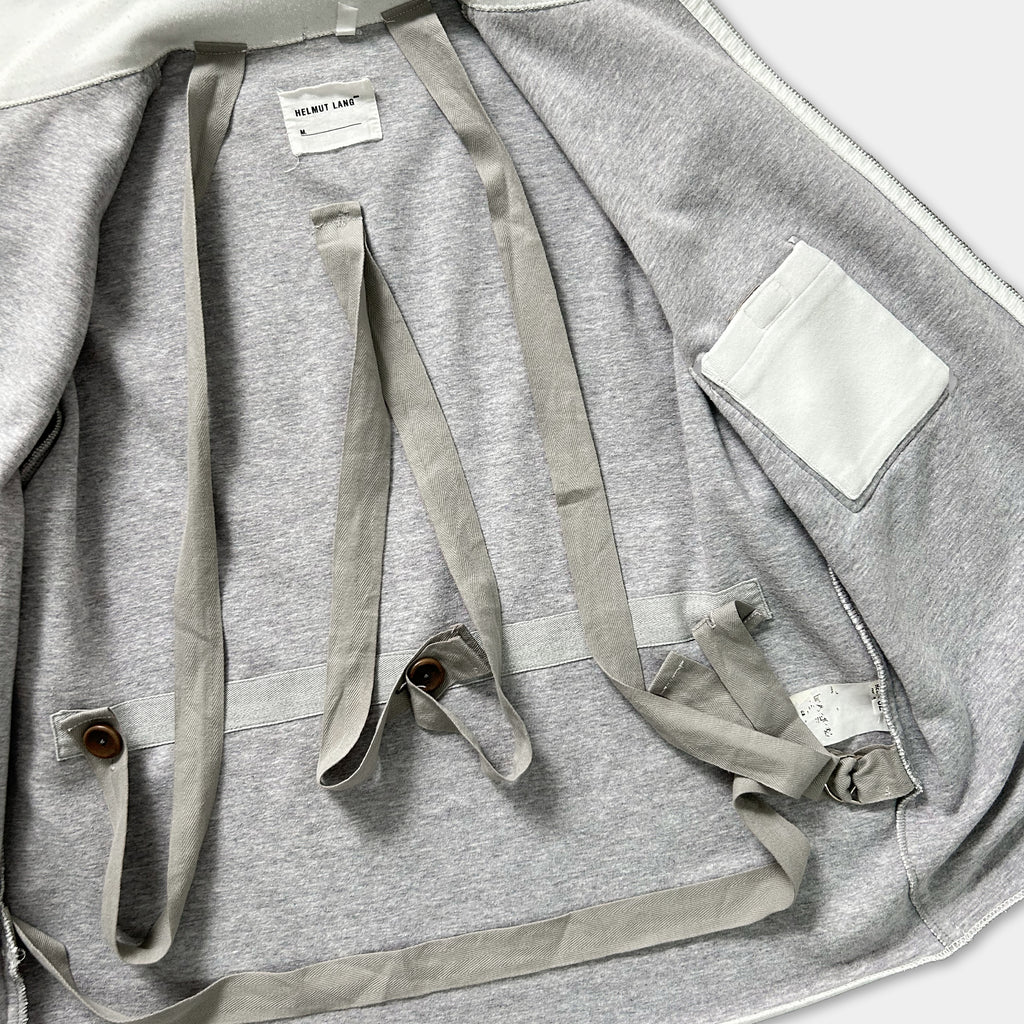 the inside of a gray sweatshirt with a white pocket and a label on the back.