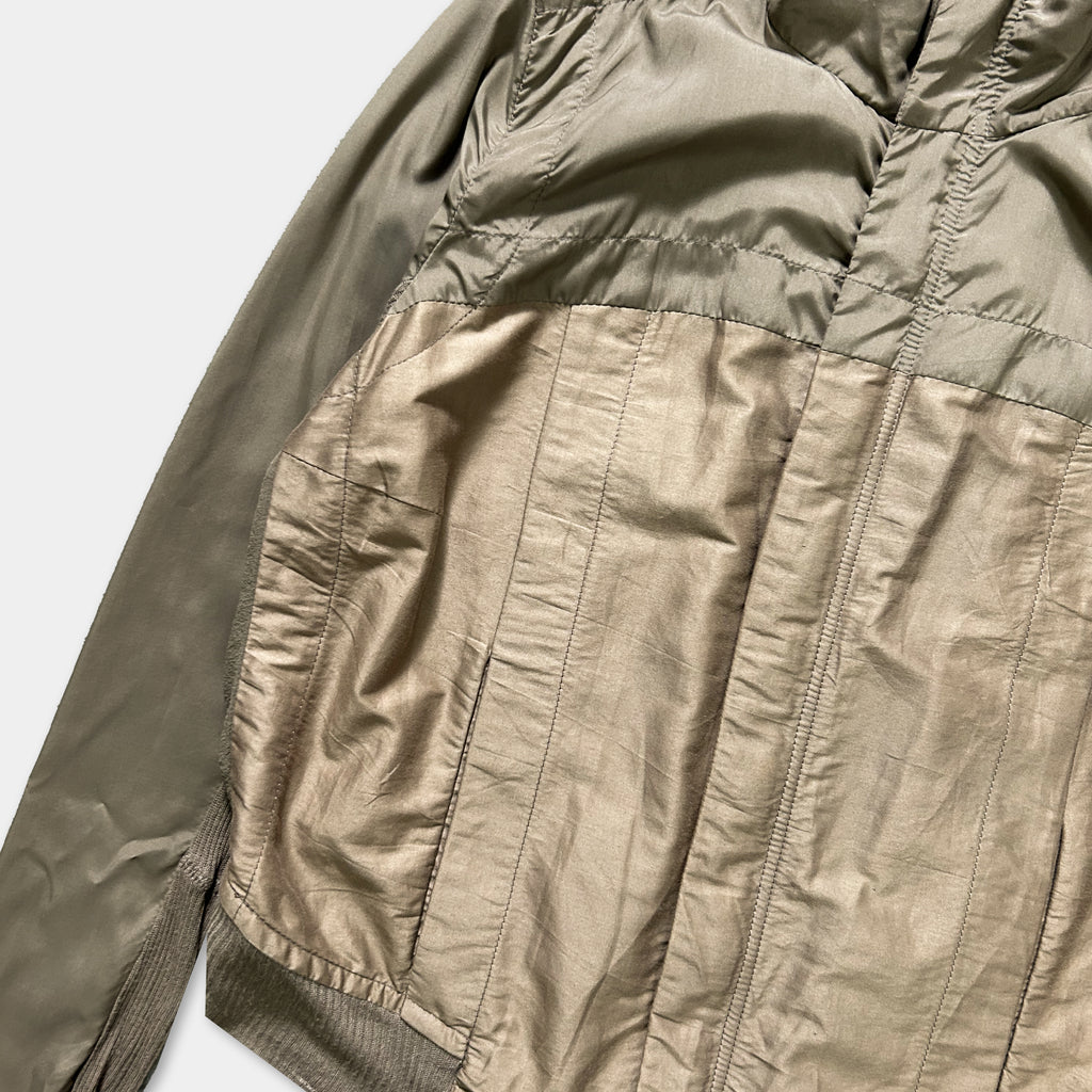 A close-up view of a beige jacket with a zipper and pockets, showing the fabric and details of the jacket.