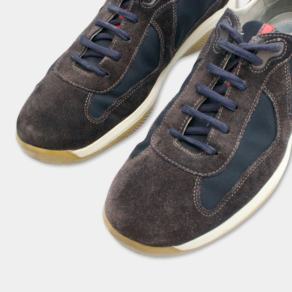 A close-up view of a pair of dark gray and white sneakers with blue laces.