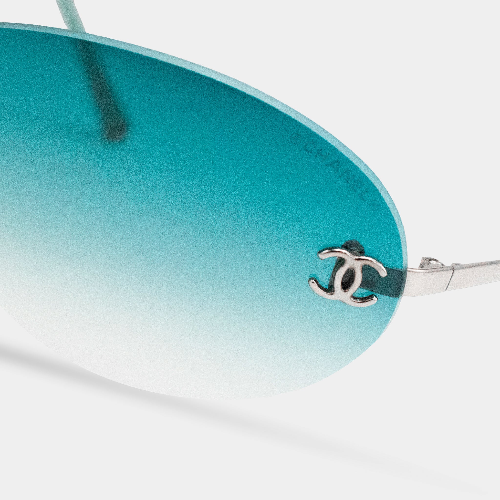 A pair of sunglasses with a silver Chanel logo on the frame.