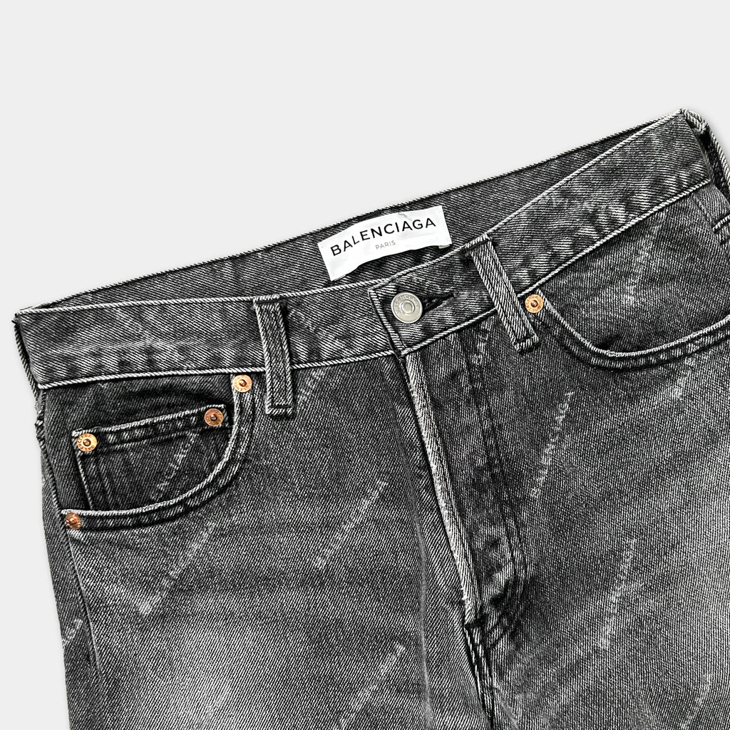 A pair of black jeans with a white label that reads "Balenciaga" on the waistband.