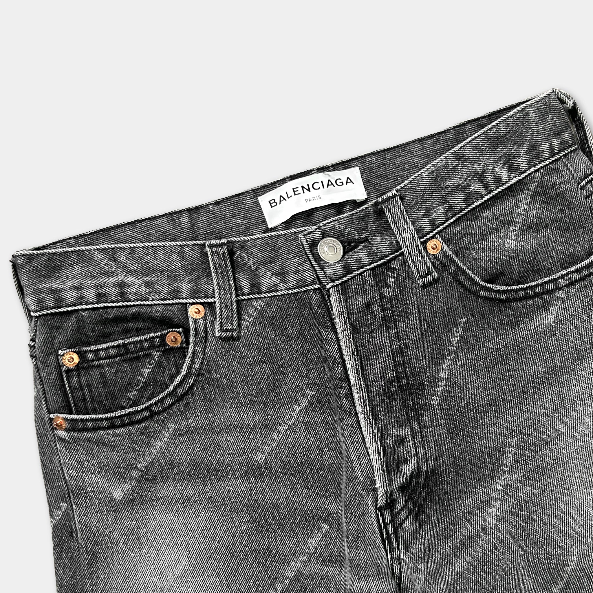 A pair of black jeans with a white label that reads "Balenciaga" on the waistband.