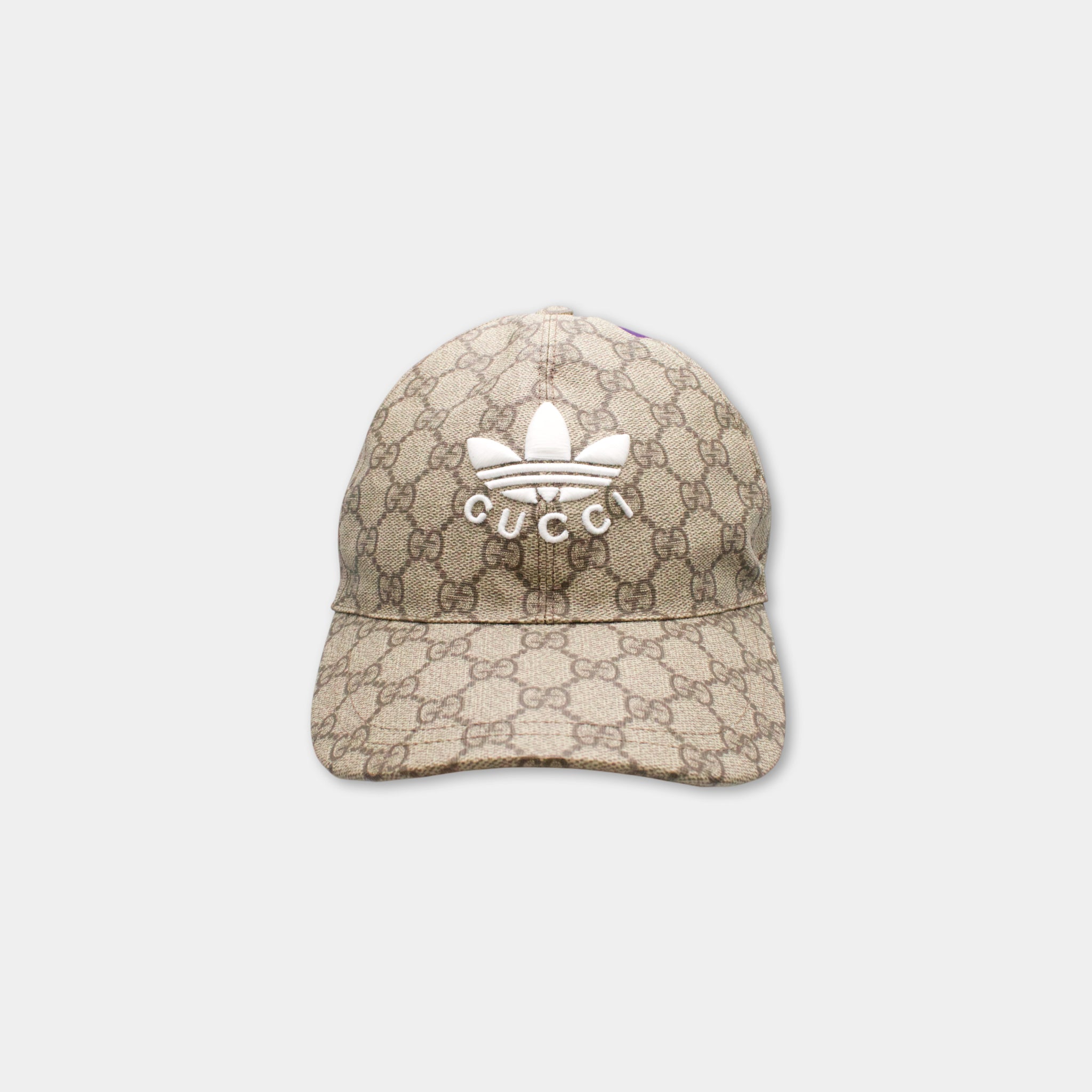 A beige Gucci-patterned baseball cap with the Gucci logo prominently displayed on the front.