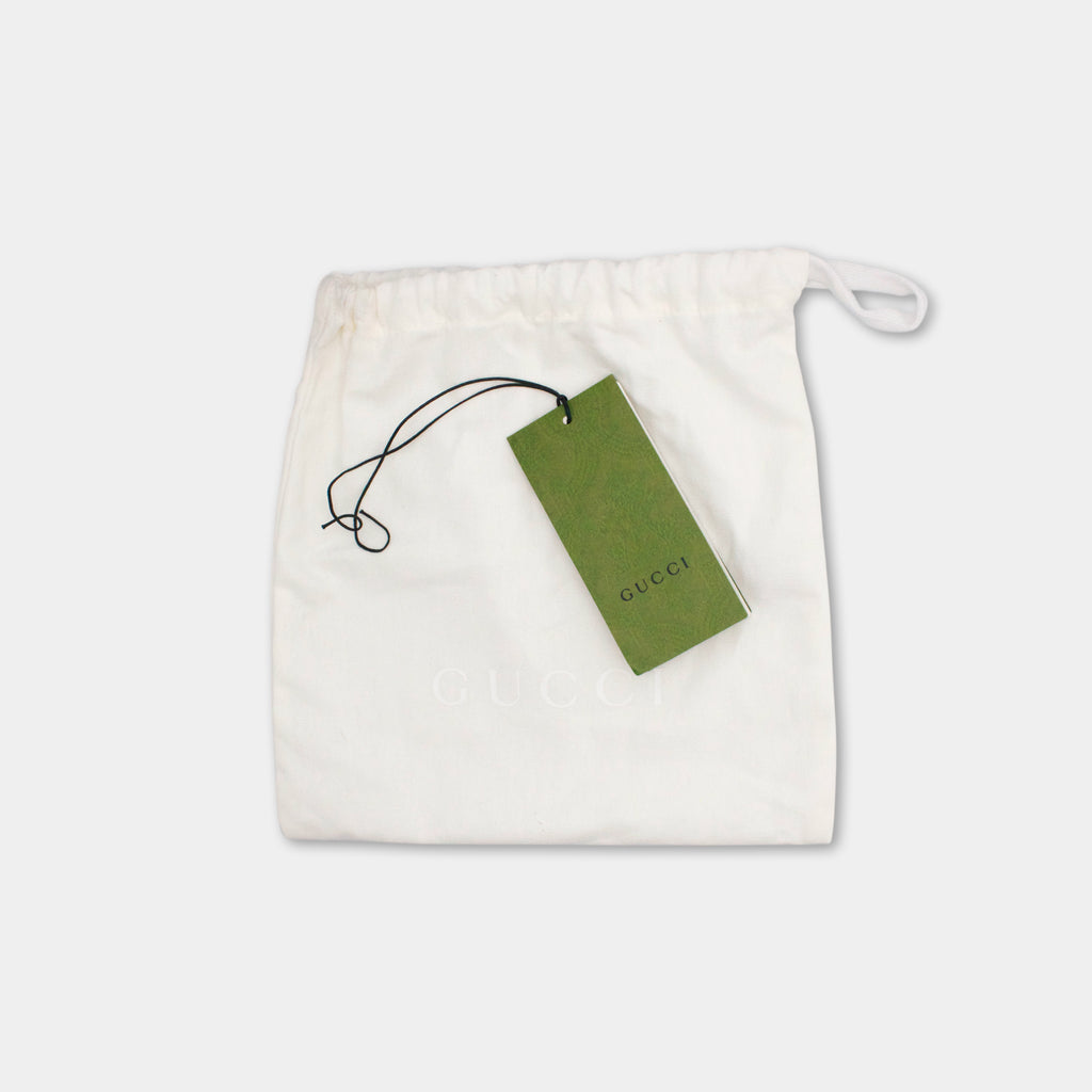 A white Gucci bag with a green tag attached to it.