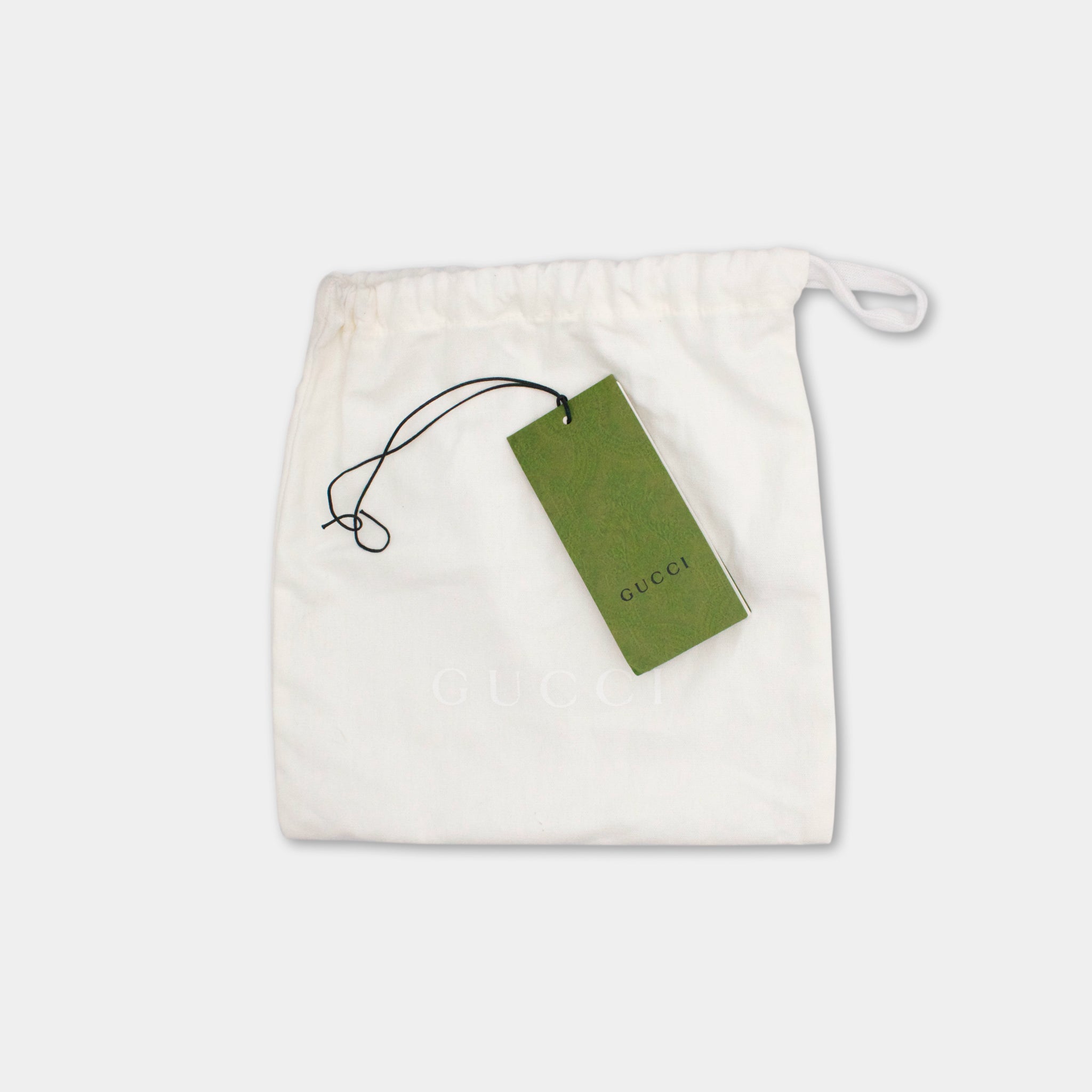 A white Gucci bag with a green tag attached to it.