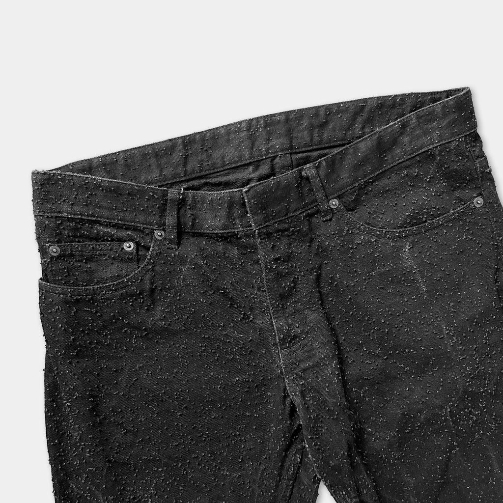 A pair of black jeans with a speckled or speckled pattern.