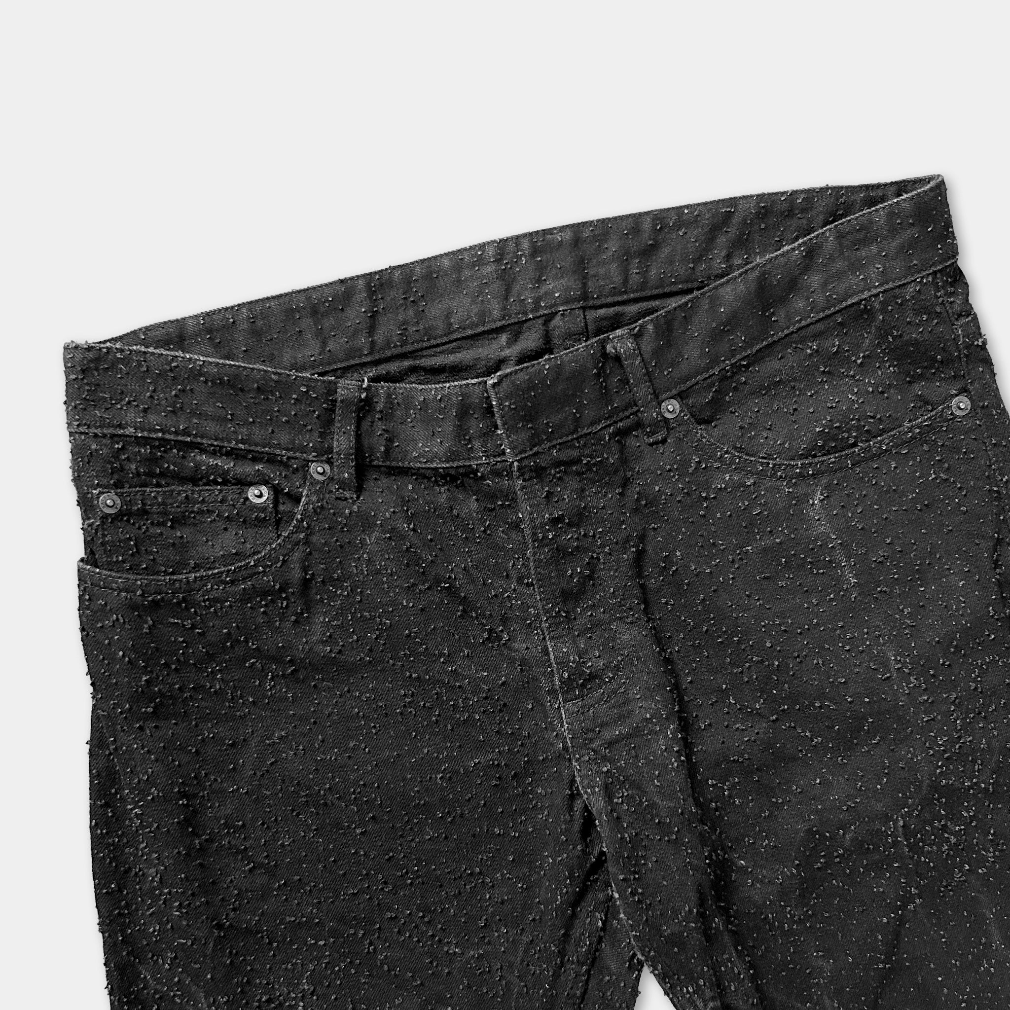 A pair of black jeans with a speckled or speckled pattern.