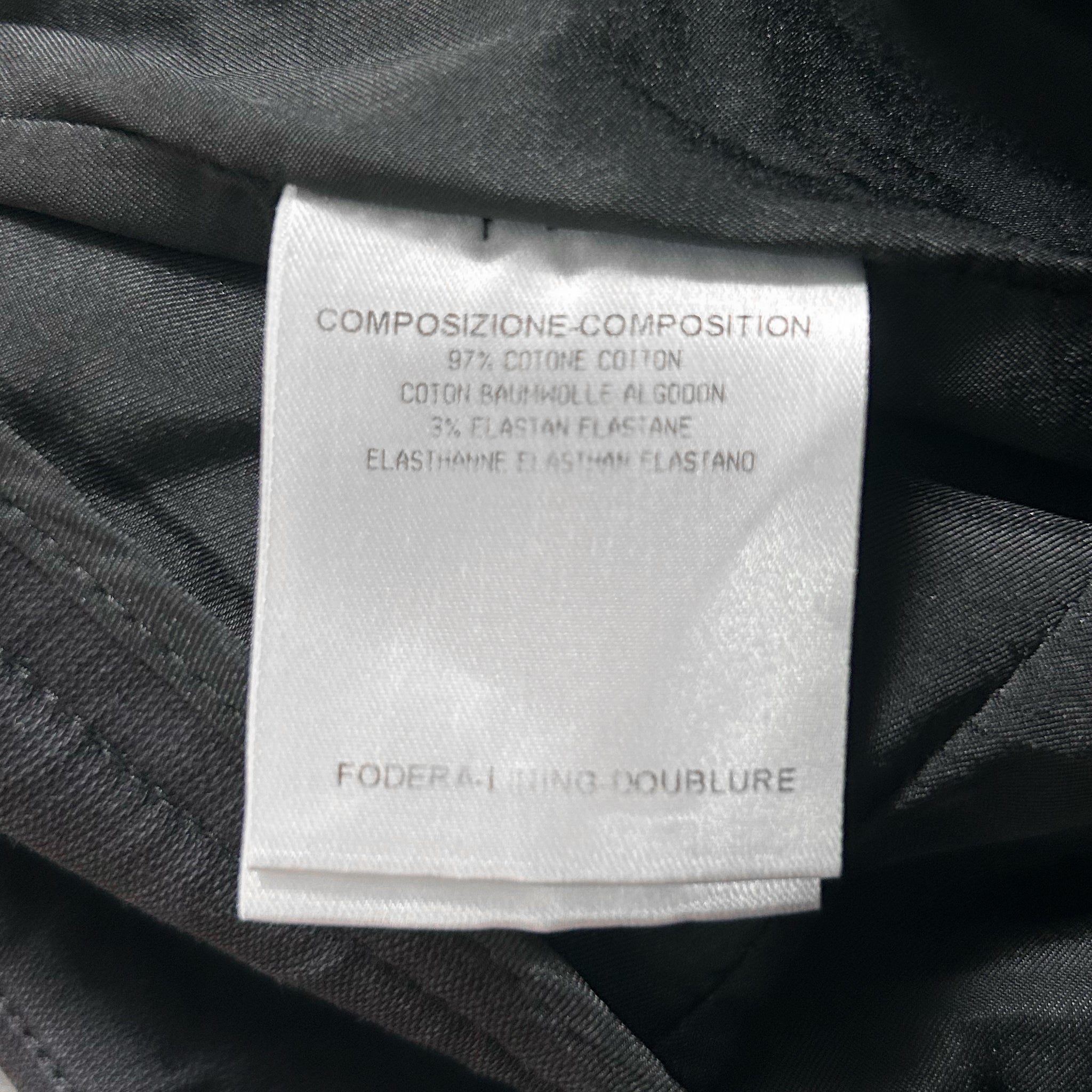 a close-up view of a label on a black fabric, likely a garment or textile. The label appears to be a label for a product, providing information about the composition and materials used.