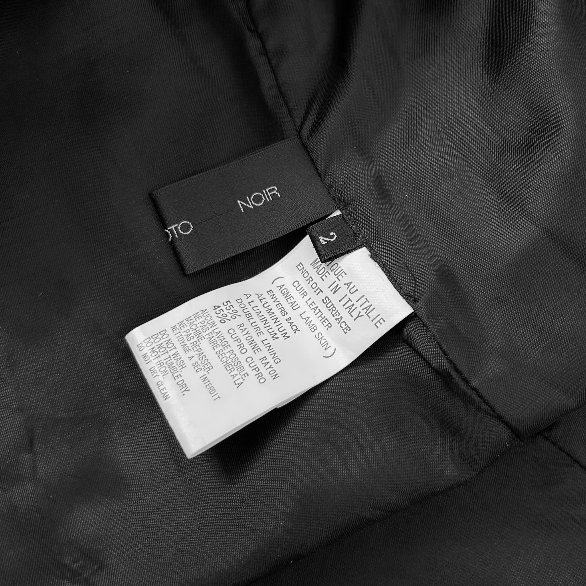 a close-up view of a black fabric, possibly a jacket or garment, with a label attached to it. The label appears to contain text and possibly a barcode or other information related to the product.