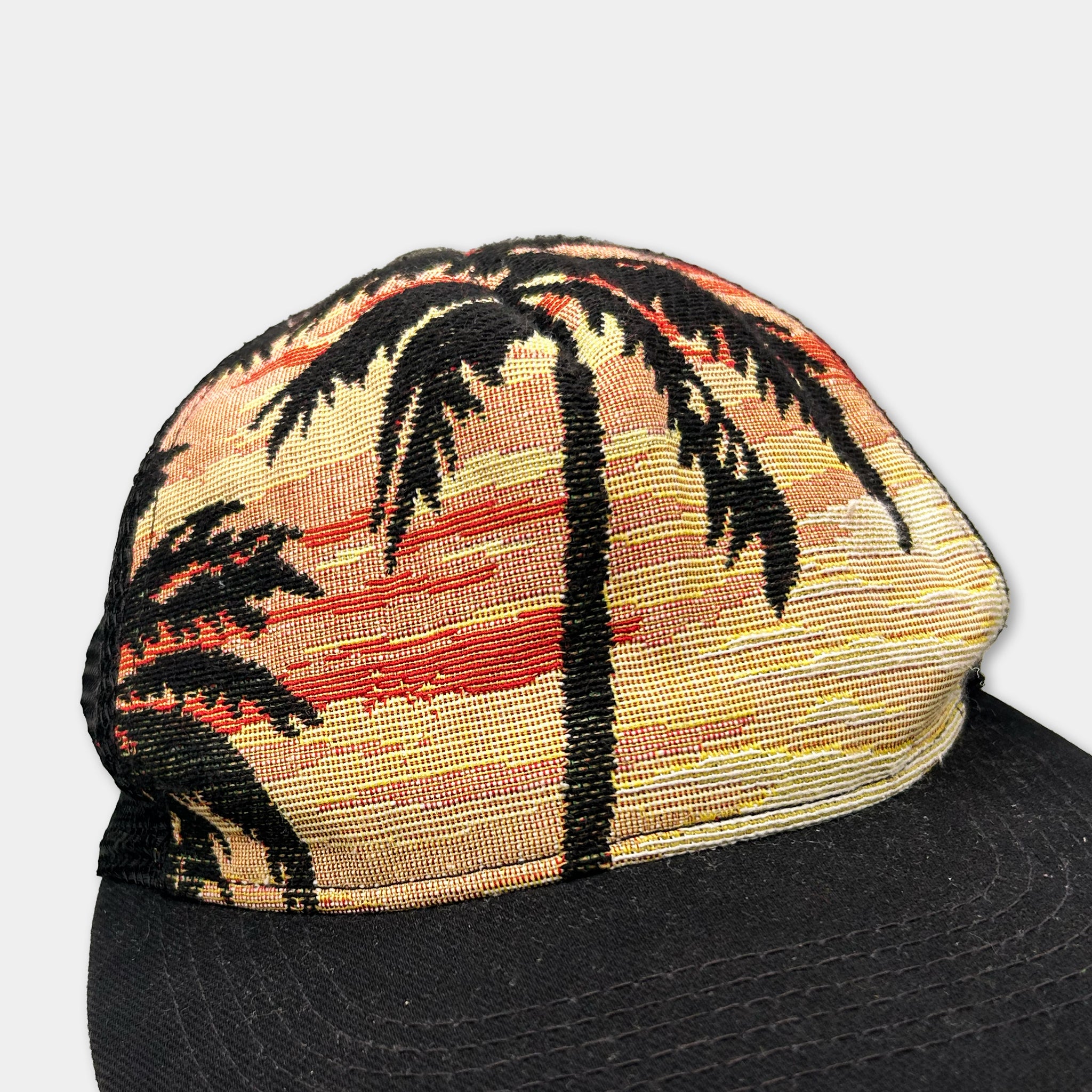 A close-up view of a colorful, patterned baseball cap with a palm tree design.