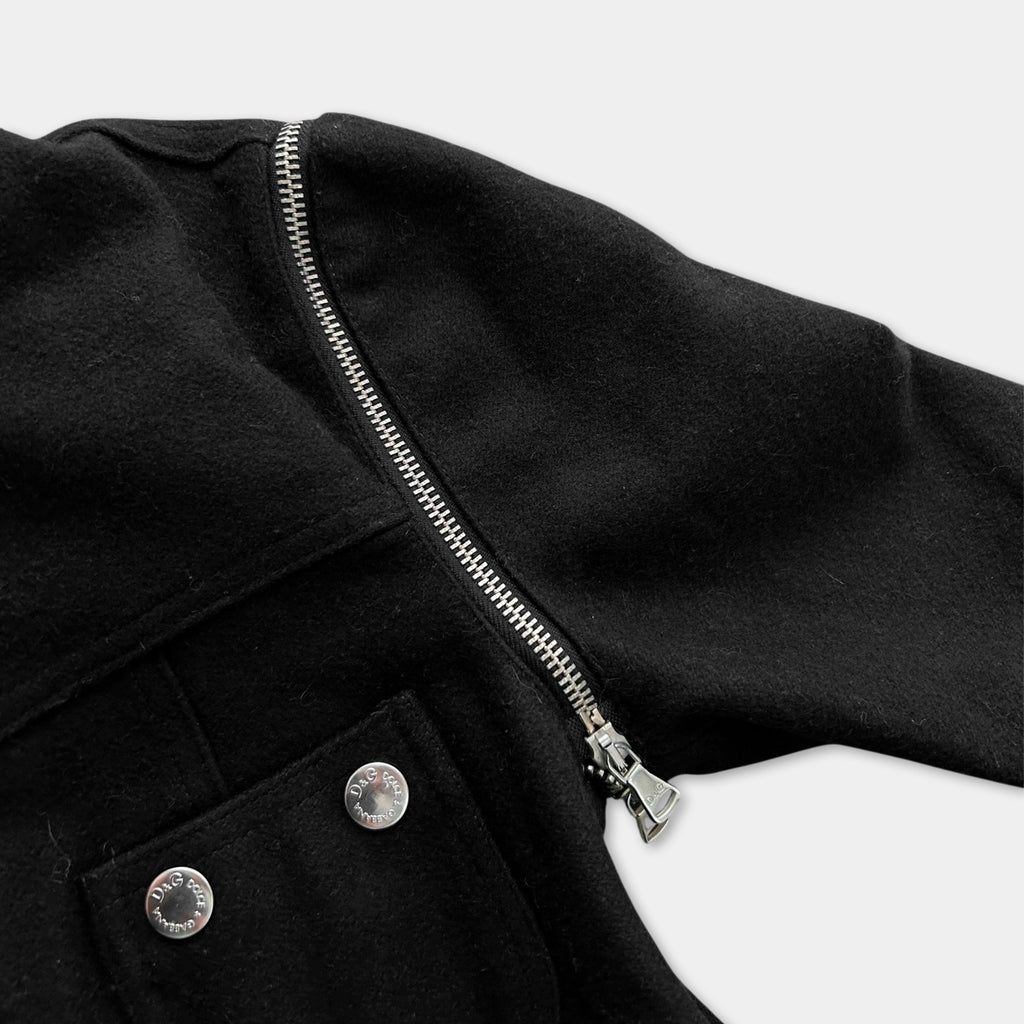 A close-up view of a black jacket with a zipper and two buttons, against a white background.