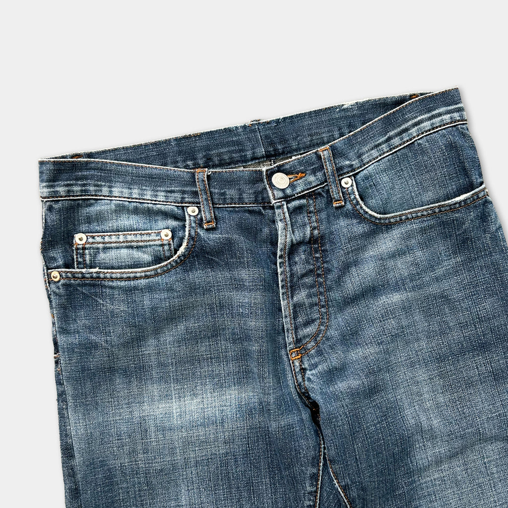 A pair of blue jeans with a button closure and a pocket on the front.