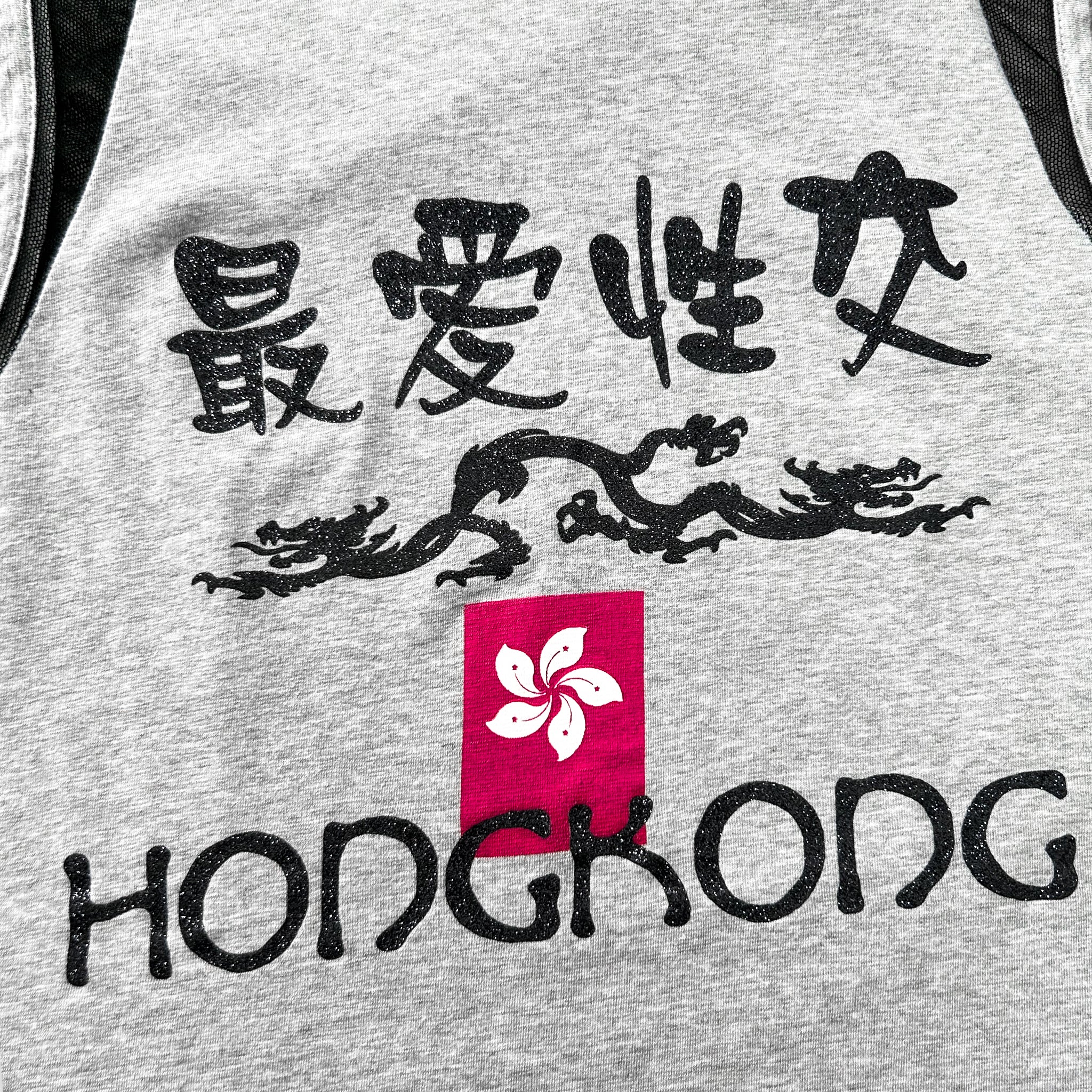 a grey tank top with black text and a red square with a white flower design, representing the city of Hong Kong.