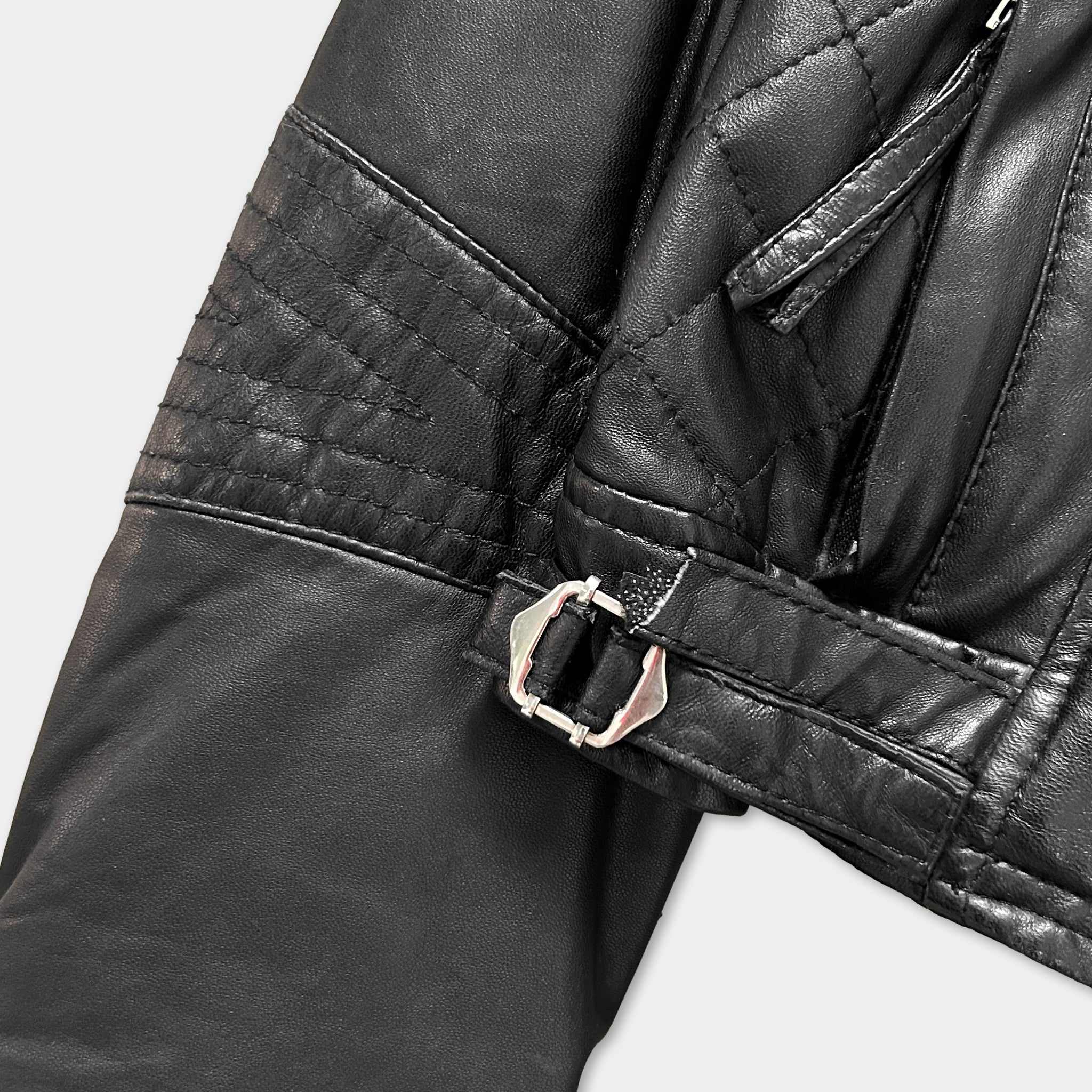 A close-up view of a black leather jacket, focusing on the zipper and buckle detail.