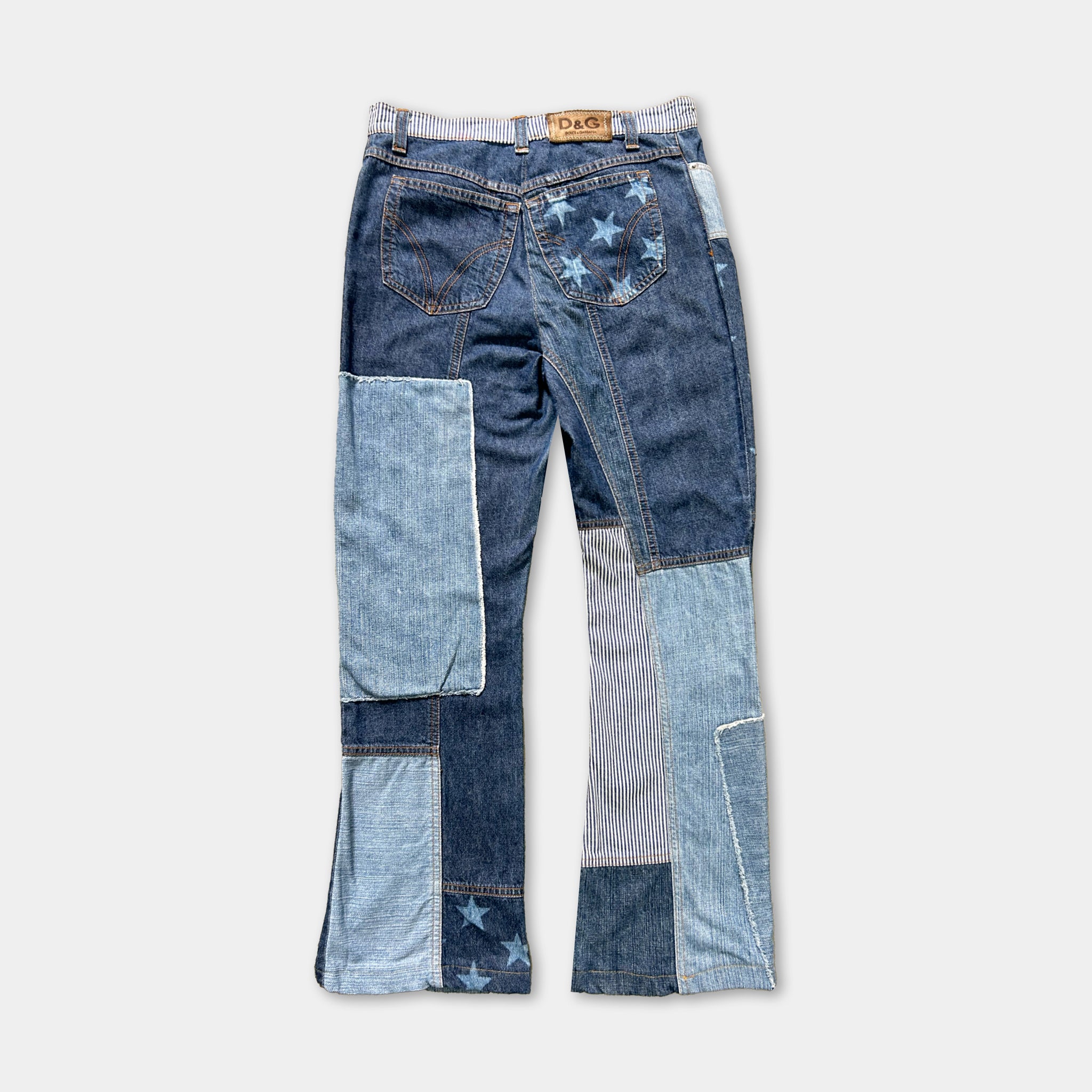A pair of blue jeans with a patchwork design, featuring various shades of blue denim and star-shaped embellishments.