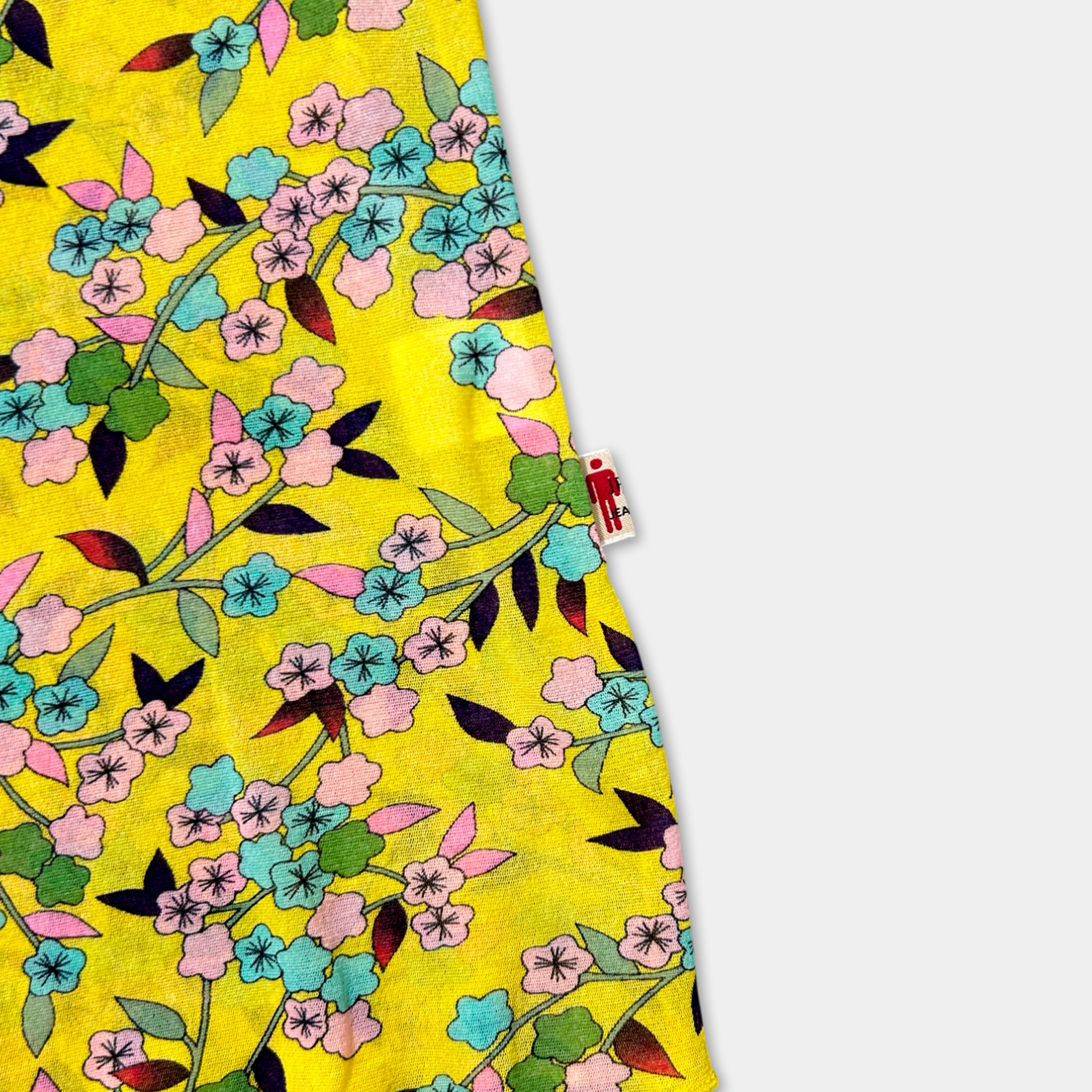a vibrant yellow fabric adorned with a floral pattern of pink, blue, and green flowers and leaves.