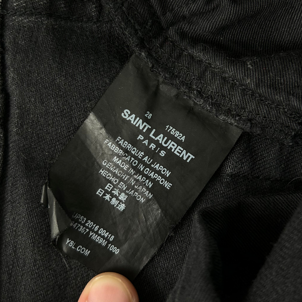 A close-up view of a black fabric, possibly a piece of clothing, with a label attached to it.
