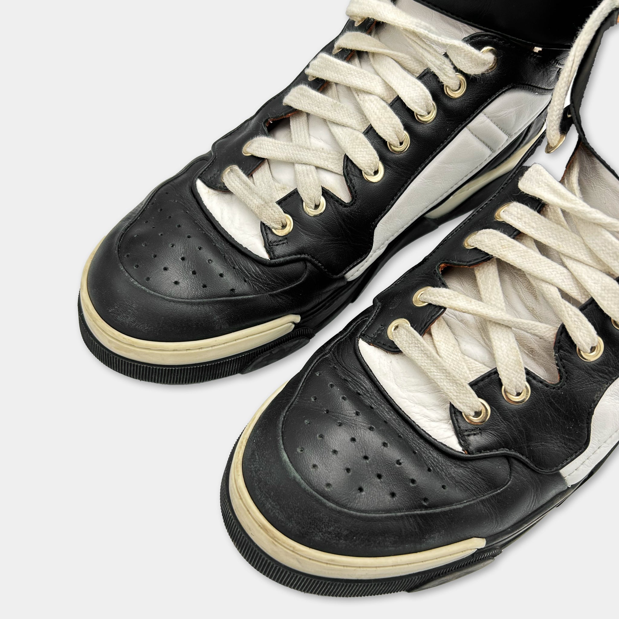 A pair of black and white sneakers with white laces and a black sole.