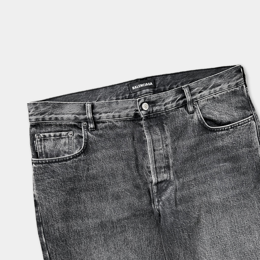 A pair of black denim jeans with the brand name "Balenciaga" printed on the waistband.