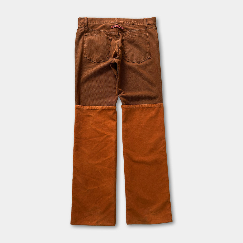 A pair of brown jeans with orange patches on the knees.