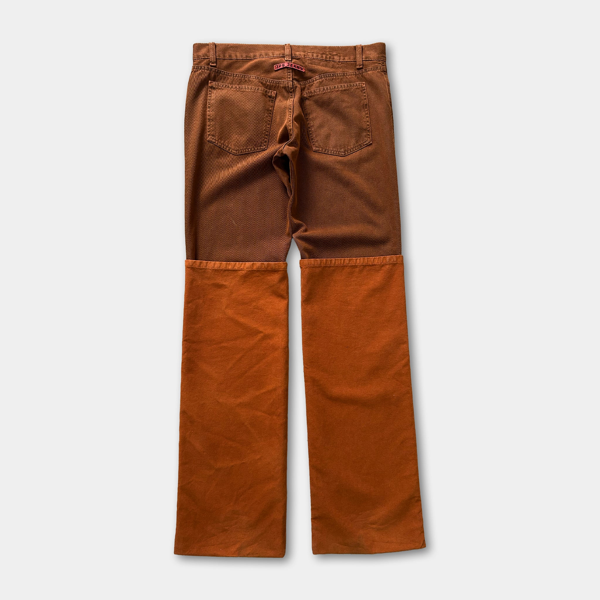 A pair of brown jeans with orange patches on the knees.