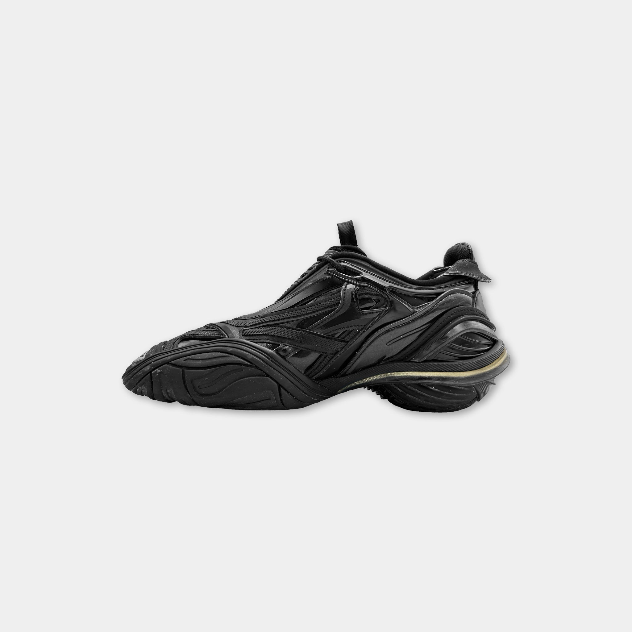 A black sneaker with a distinctive design and a gold accent detail.