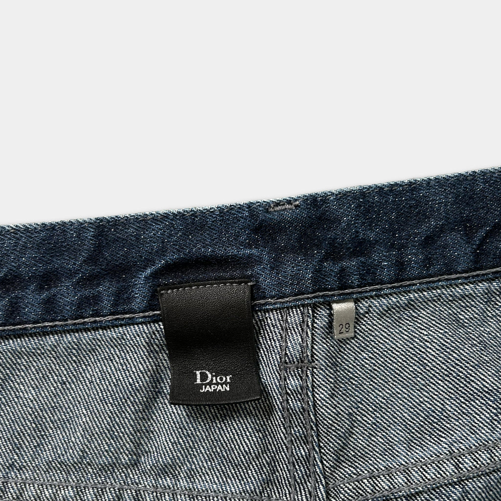 a close-up view of a pair of blue denim jeans, with a black label attached to the waistband.