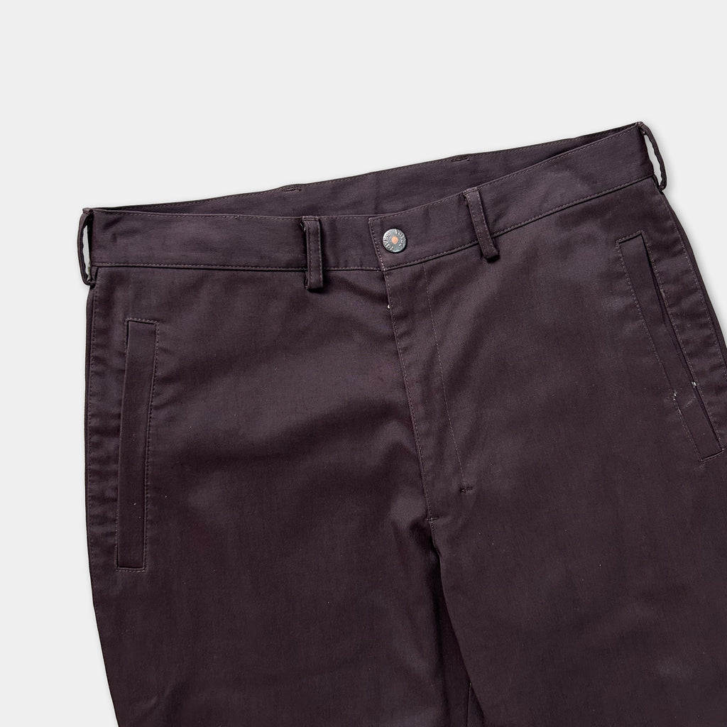 A pair of dark-colored pants with a button waistband and two pockets.