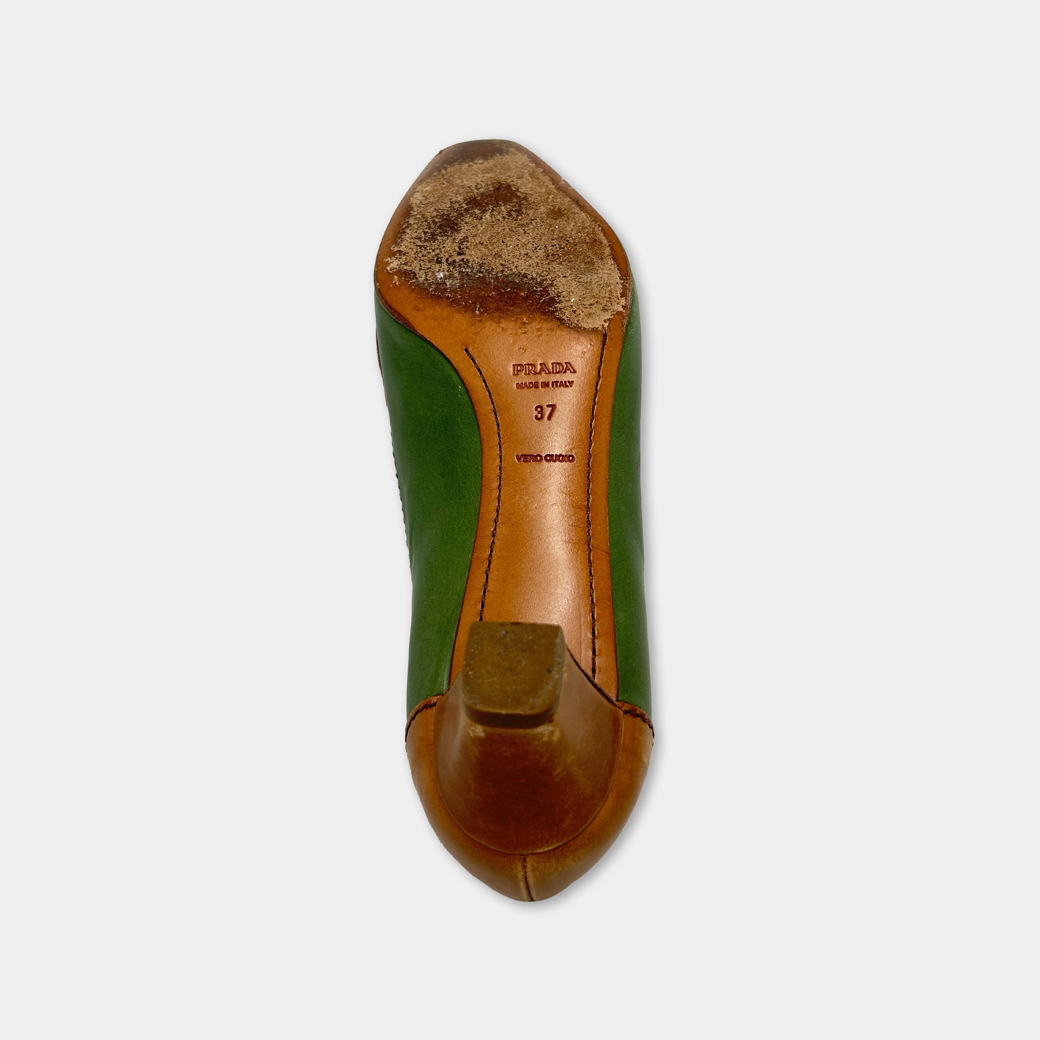 A worn and dirty shoe with a green and brown leather upper and a brown leather sole, showing signs of wear and tear.