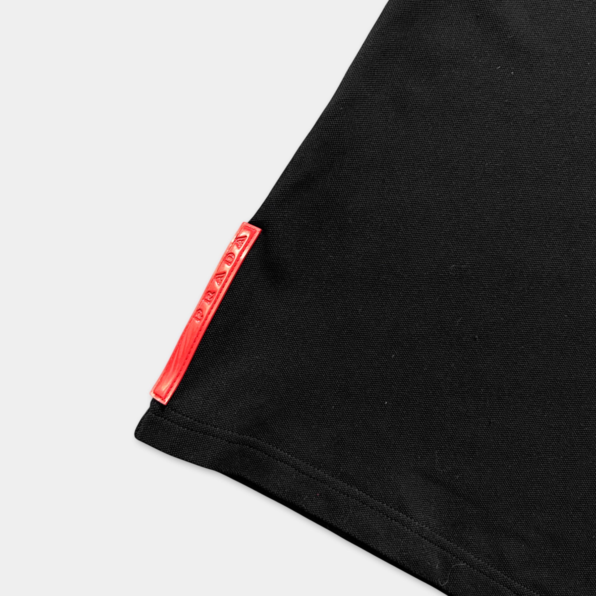 A close-up view of a black fabric, possibly a shirt or garment, with a red tag or label attached to it.