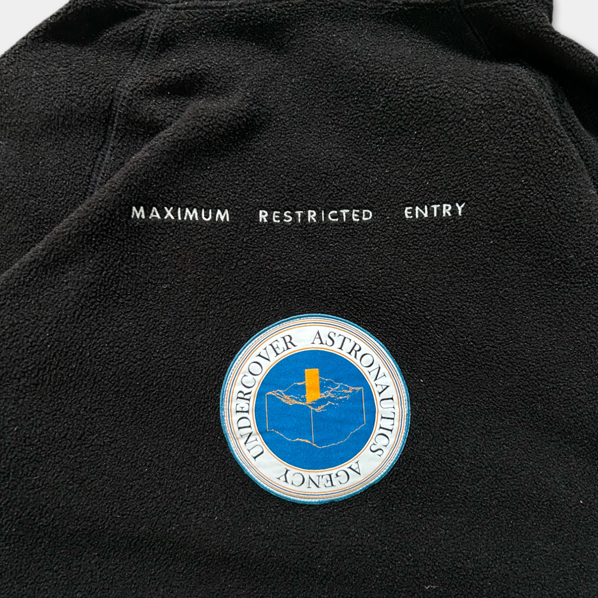 a black jacket with white text and a circular logo on the back.