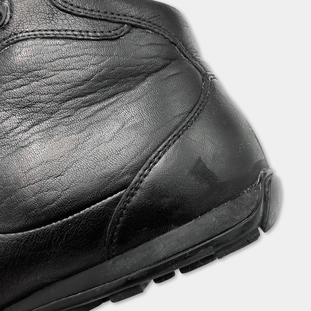 A close-up view of a black leather boot, showing the sole, heel, and part of the upper part.