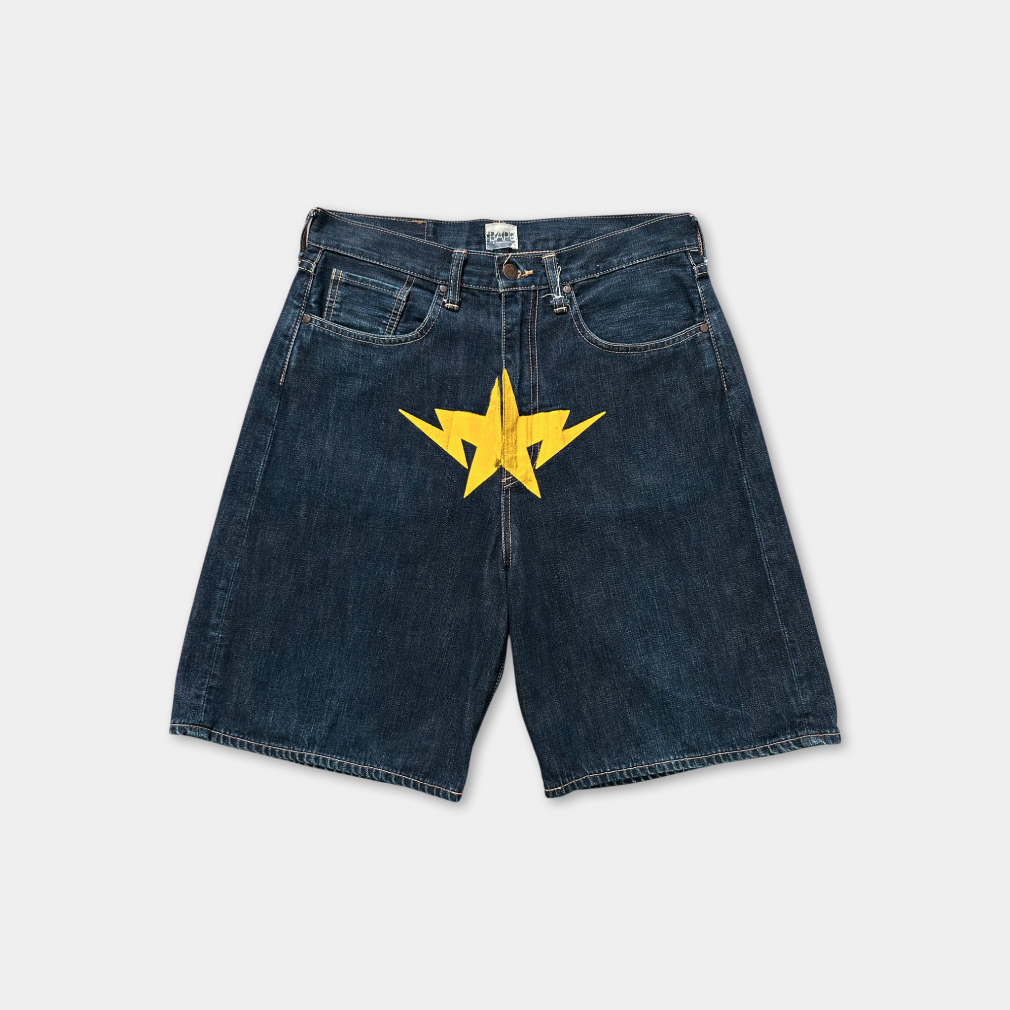 A pair of blue denim shorts with a yellow star design on the front.