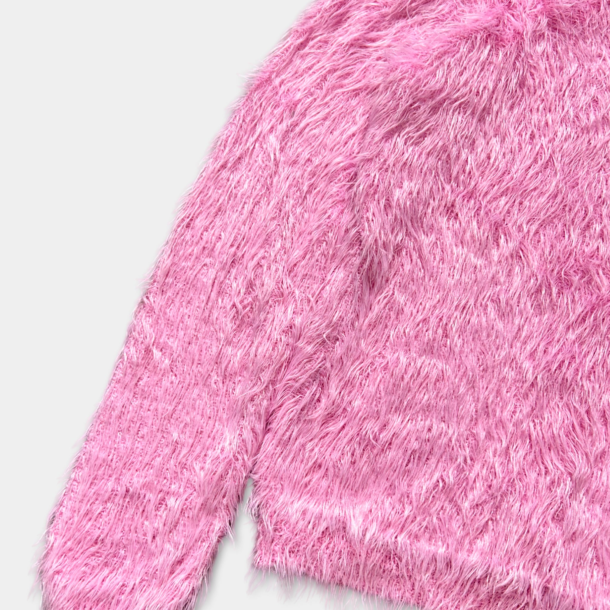 A close-up image of a pink fuzzy sweater or garment.