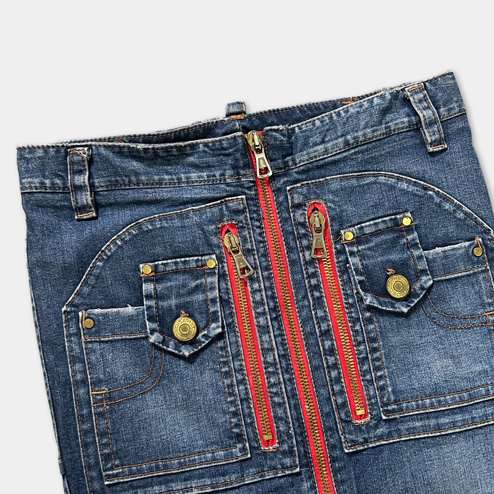 A pair of blue jeans with red zippers and gold buttons, featuring multiple pockets and zippers.