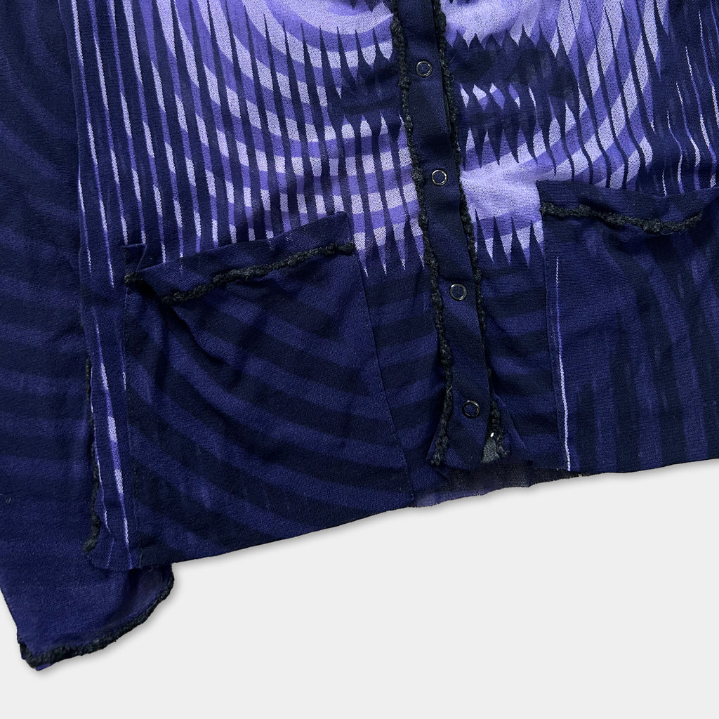 a close-up view of a dark blue fabric with a pattern of purple and white stripes. The fabric appears to be a jacket or cardigan, with a button visible on the front.