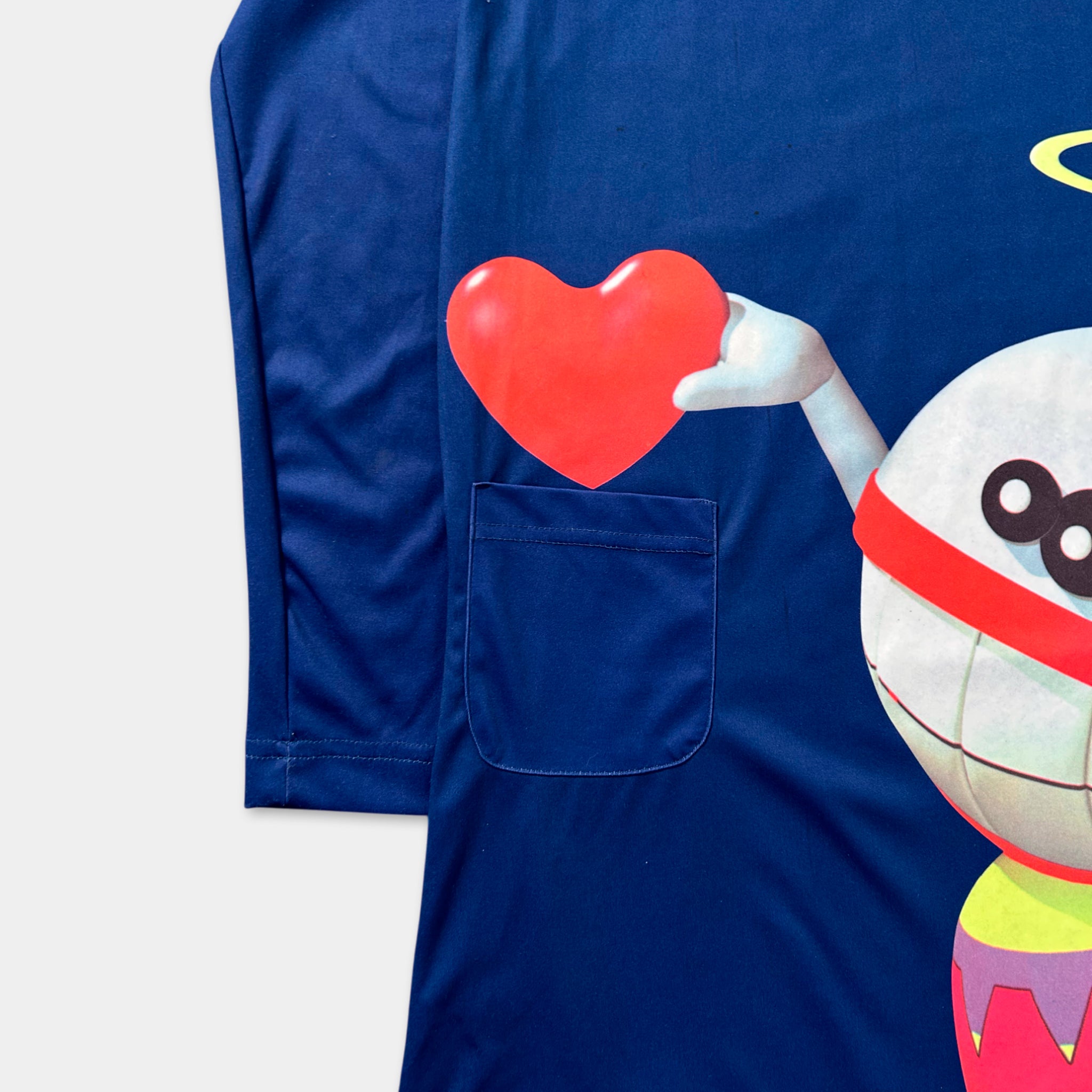 a blue long-sleeved shirt with a large graphic of a smiling character holding a red heart.