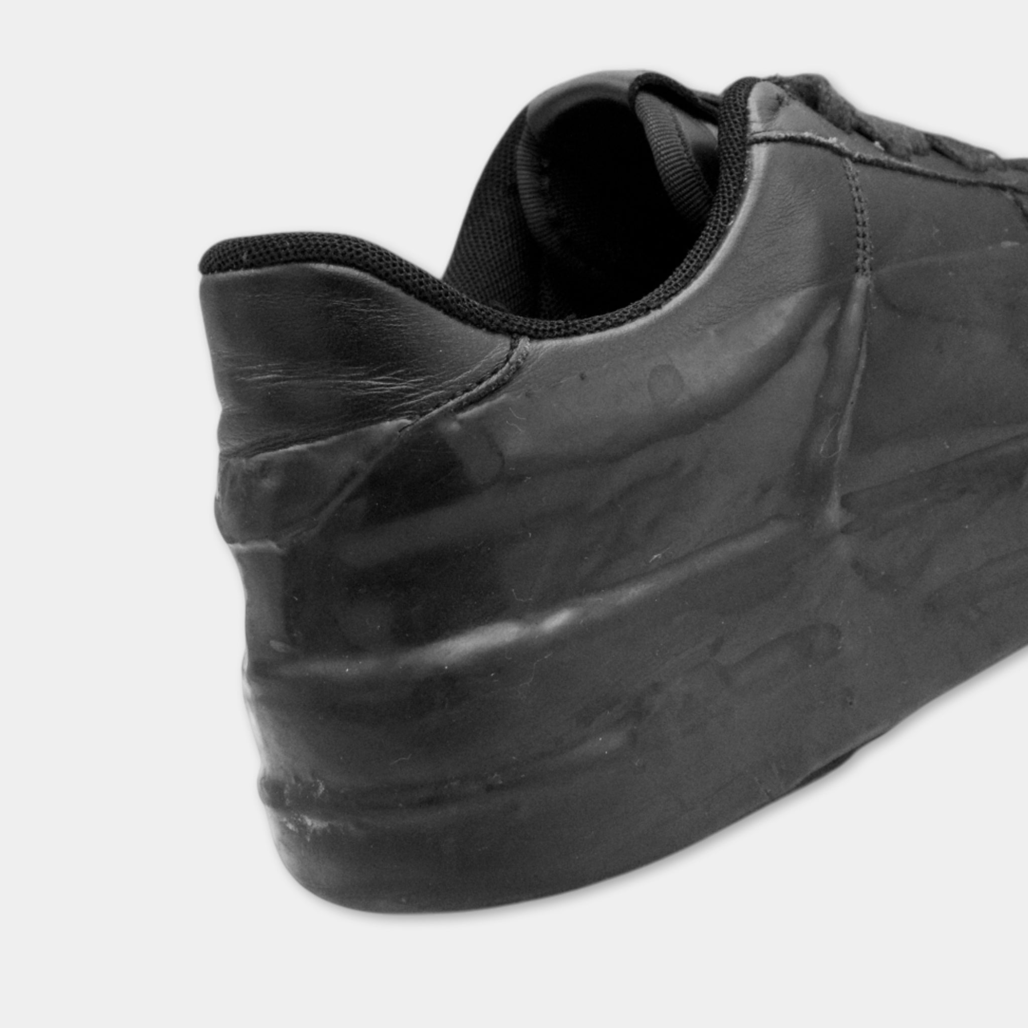 A close-up view of a black, worn-out shoe with visible signs of wear and tear, including scuffed and scuffed-out areas.